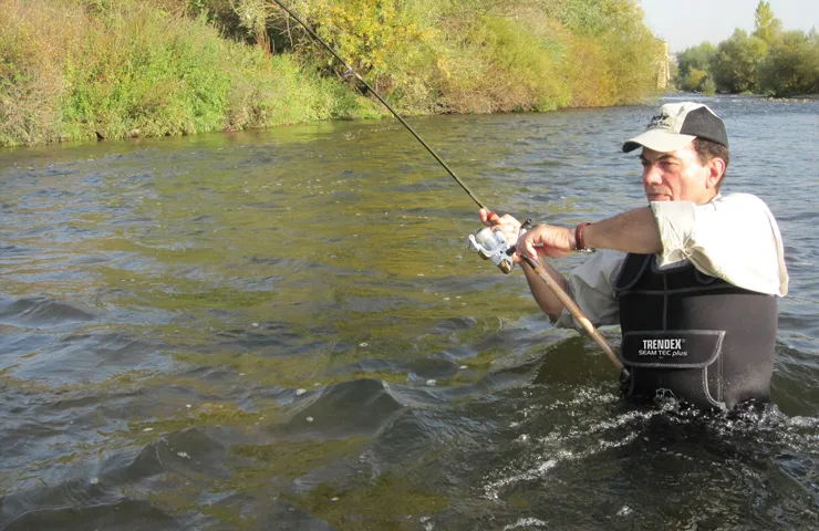 Angler steht im Fluss und angelt.